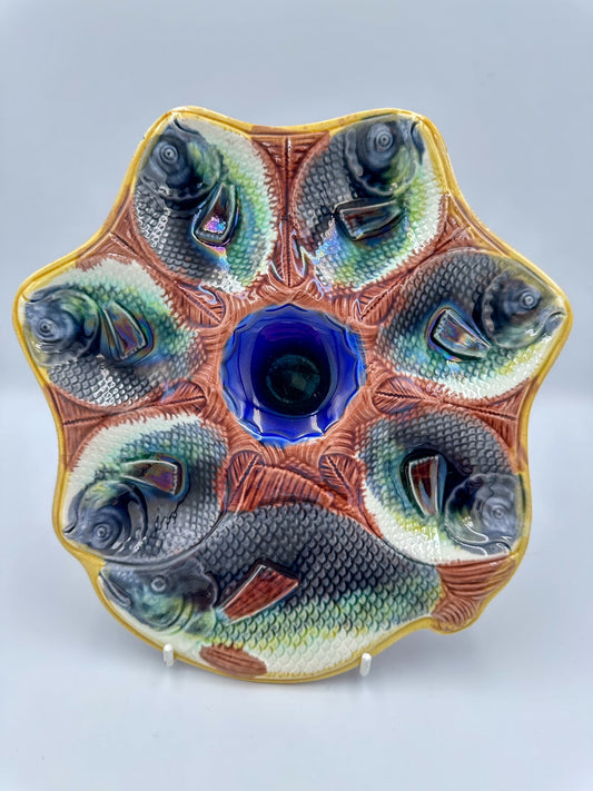 An Antique ceramic serving platter with a central blue cobalt well and surrounding yellow ochre rim, molded with six fish figures.
