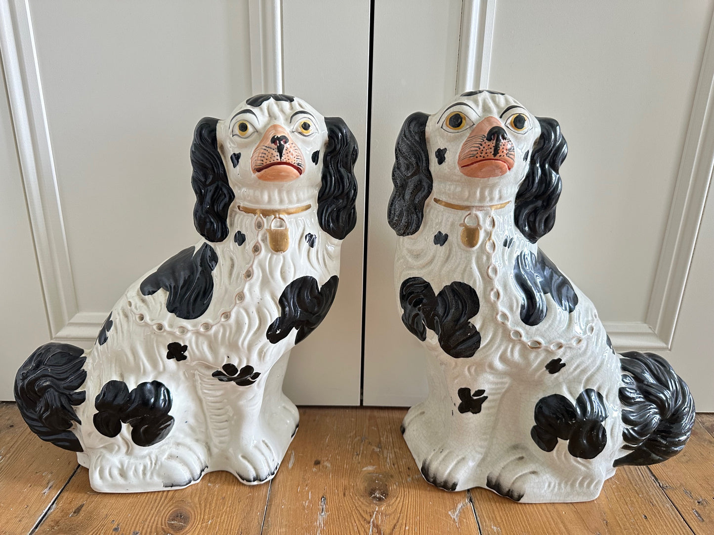 A pair of large black and white Staffordshire Spaniel dogs with hand-painted facial expressions, sitting upright.