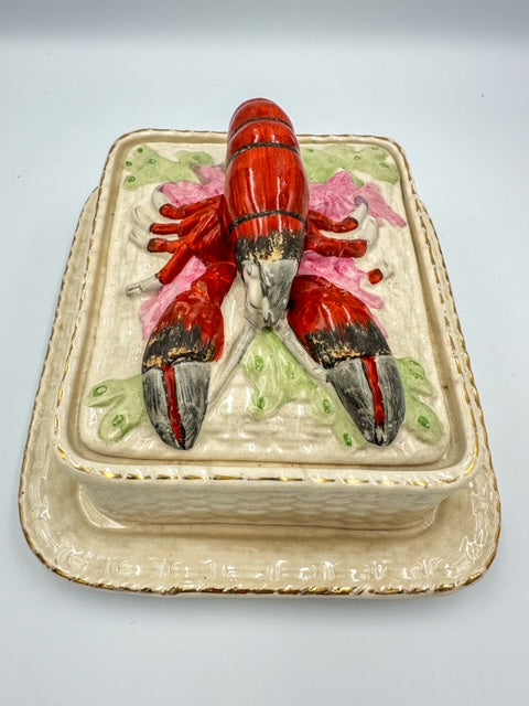 A vintage ceramic sardine dish with a hand-painted lobster relief lid on top, featuring a cream basketweave design and gilt edges.