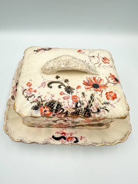 An ornate porcelain sardine dish with floral and geometric Imari patterns in gold, beige, and multicolor.