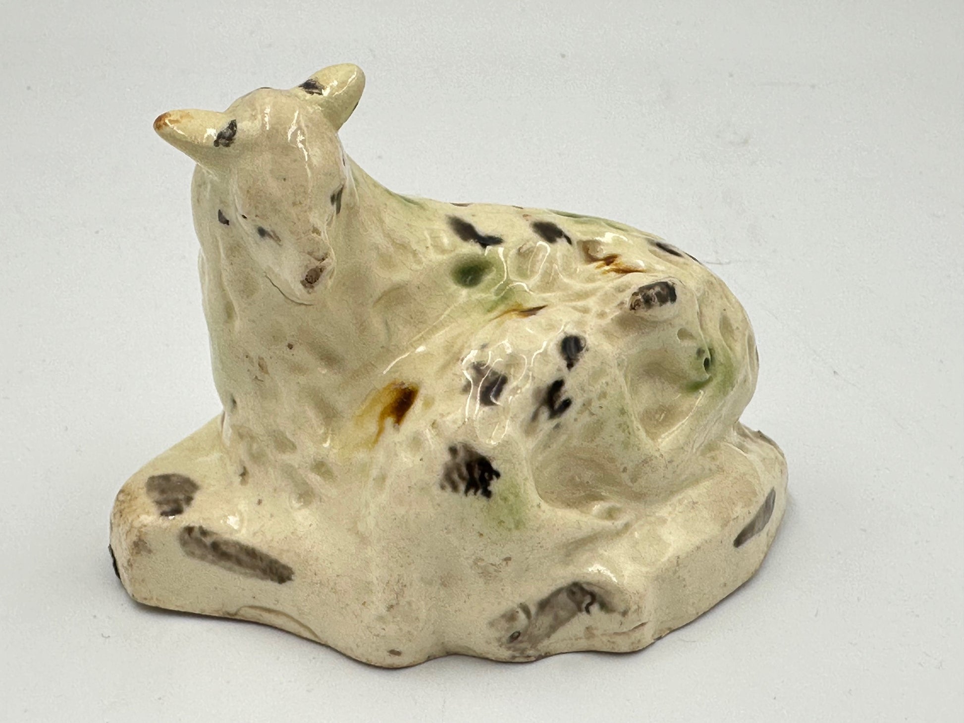 Antique ceramic figurine of a ewe and lamb with a green, black, and brown tortoise shell pattern on a flatback base.