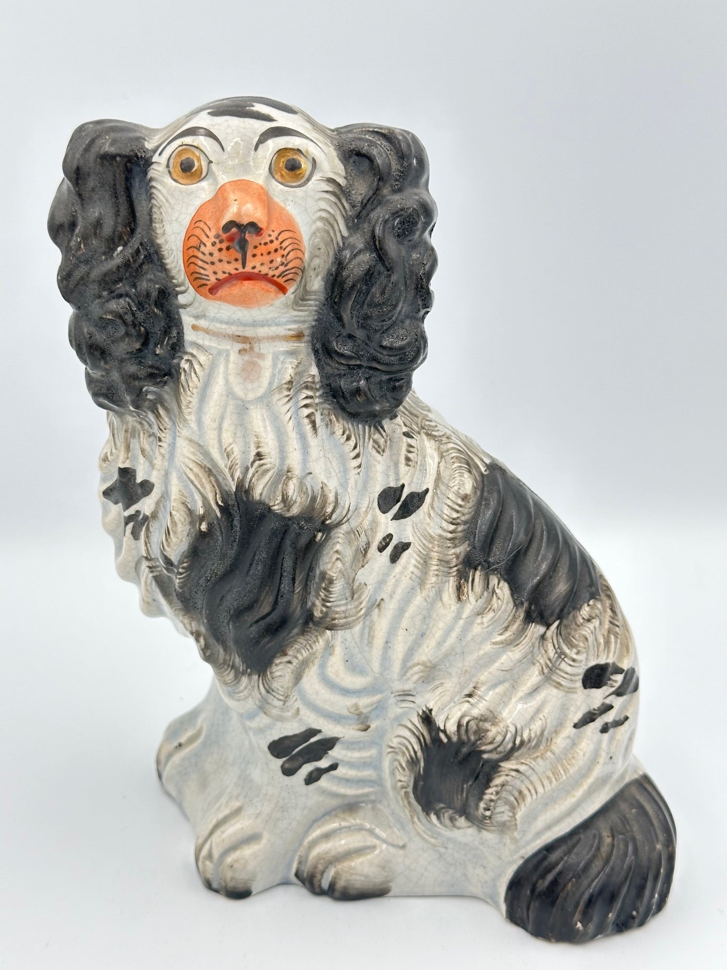 A black and white Staffordshire King Charles Spaniel dog figurine from the 1860s, showing signs of wear and aging.