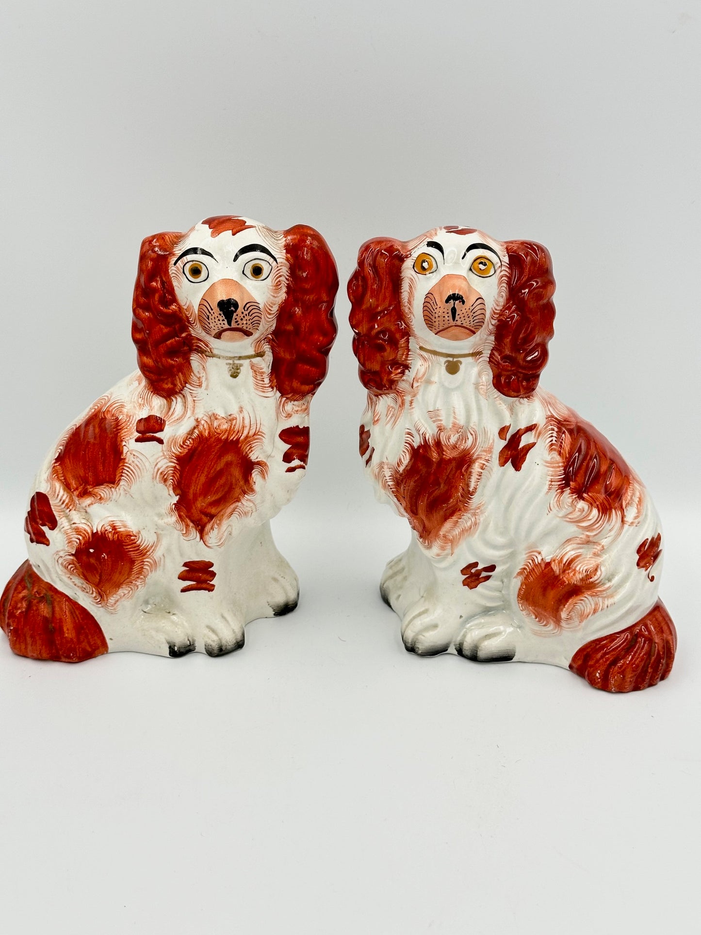 A pair of antique red Staffordshire King Charles Spaniels with hand painted features and a gilt collar and lock.
