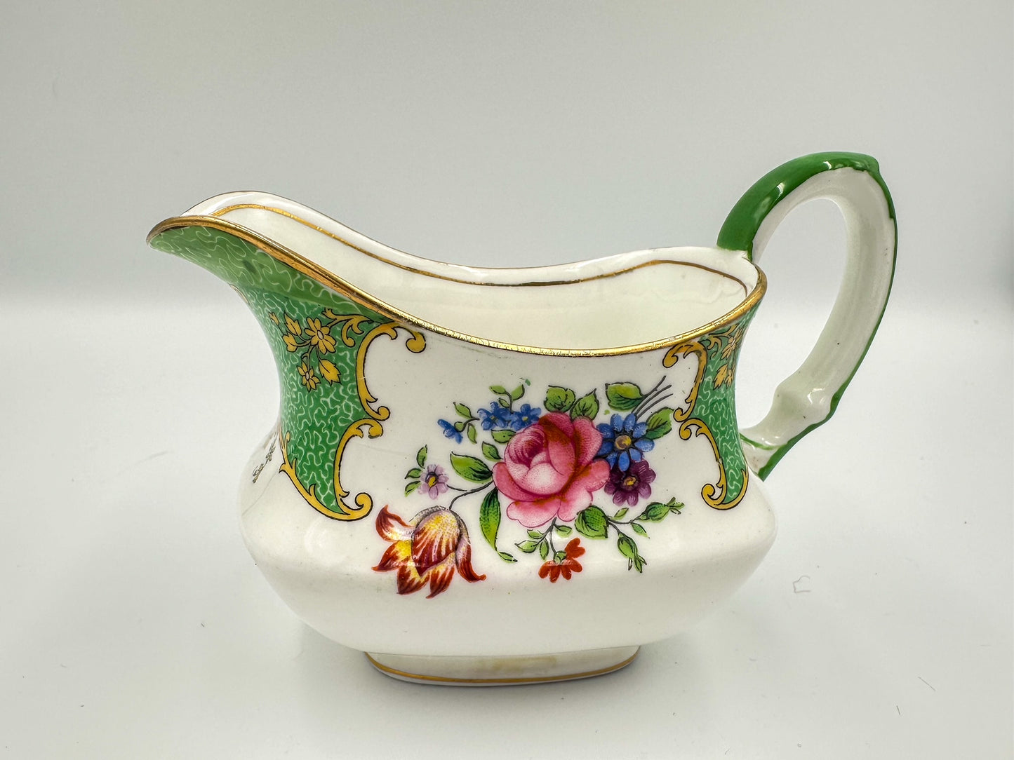 A green, white, and multicolored floral-patterned Aynsley bone china creamer pitcher.