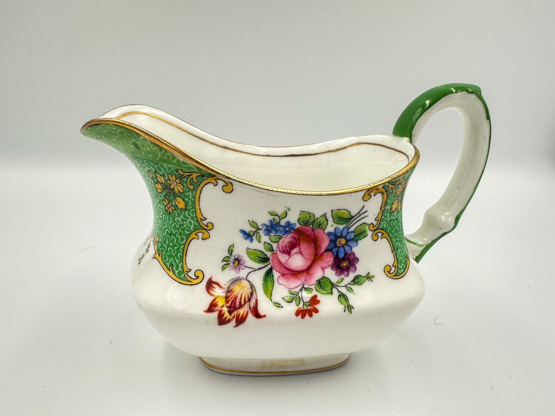 A green, white, and multicolored floral-patterned Aynsley bone china creamer pitcher.