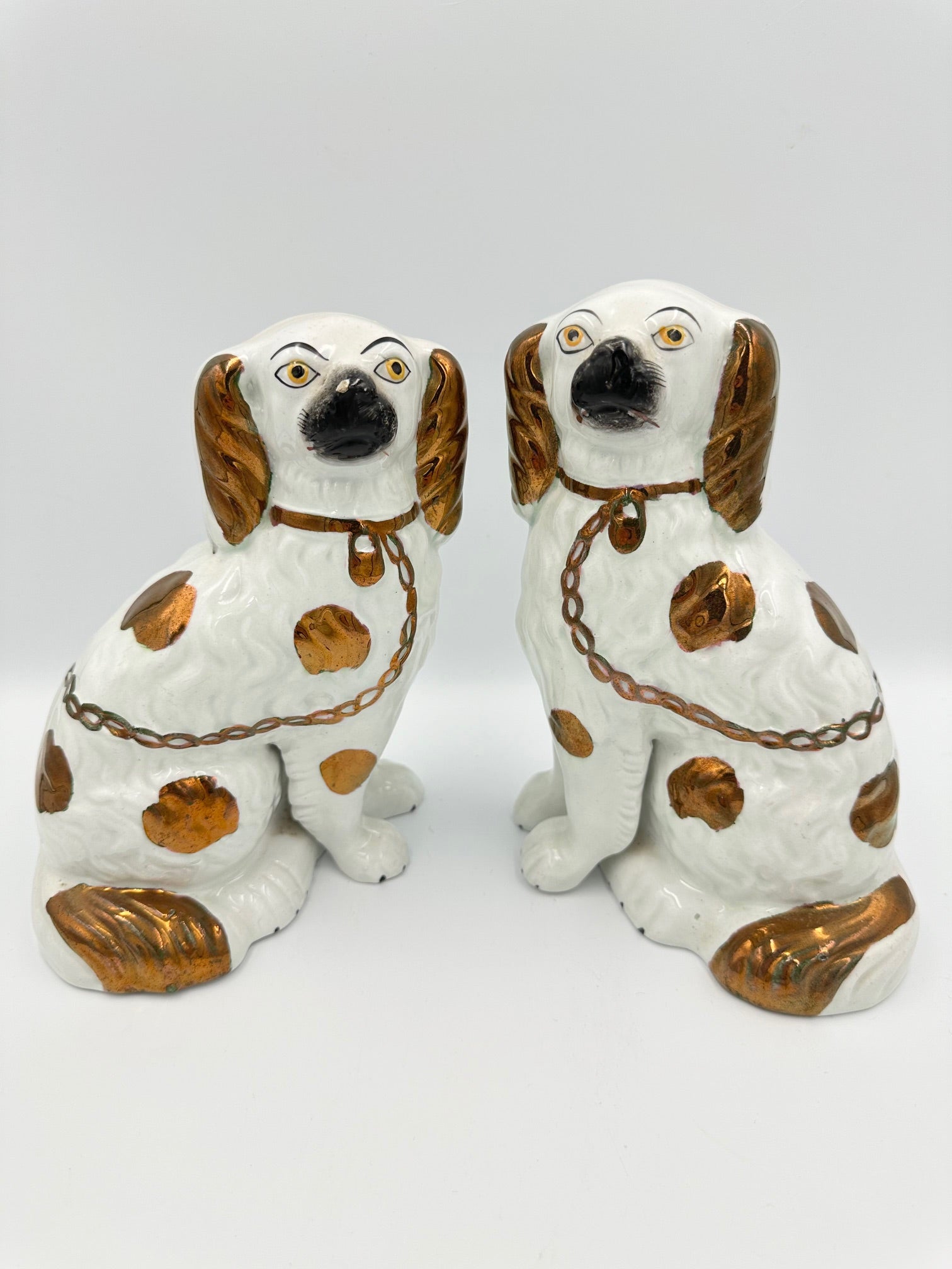 A pair of copper lustre Staffordshire King Charles Spaniel figurines with hand-painted expressions and separate legs.