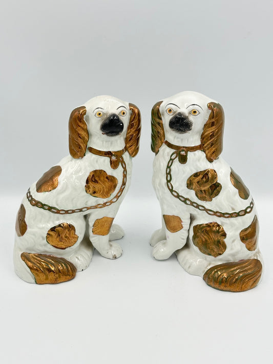 A pair of copper lustre Staffordshire King Charles Spaniels with separate legs, hand painted faces, and a chain detail.