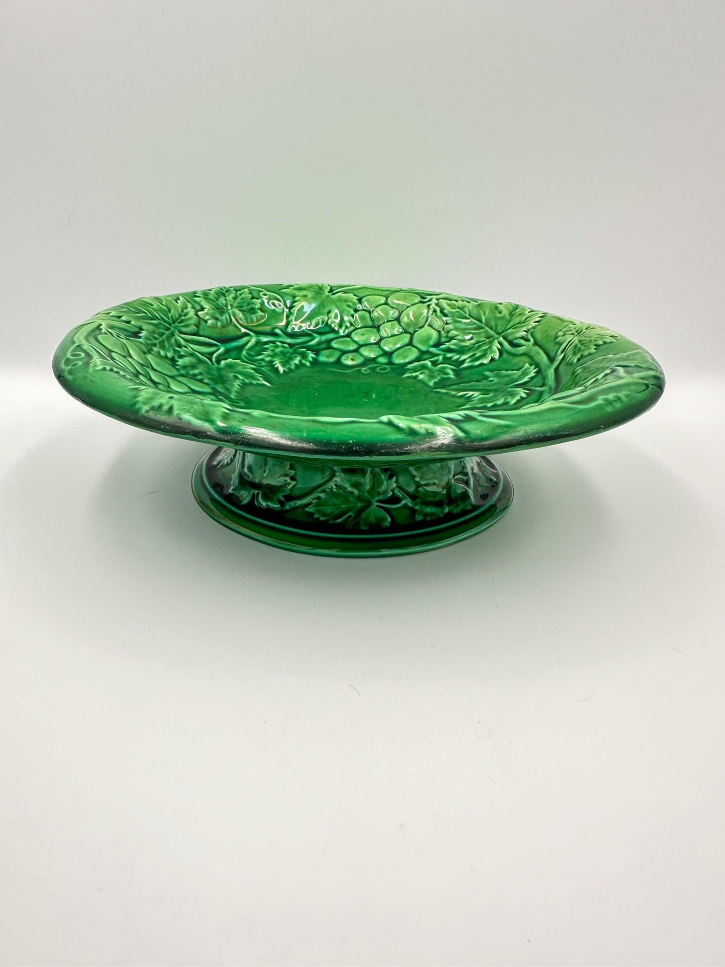 A late 19th century English green majolica footed bowl with a grape vine pattern, unmarked on the bottom.