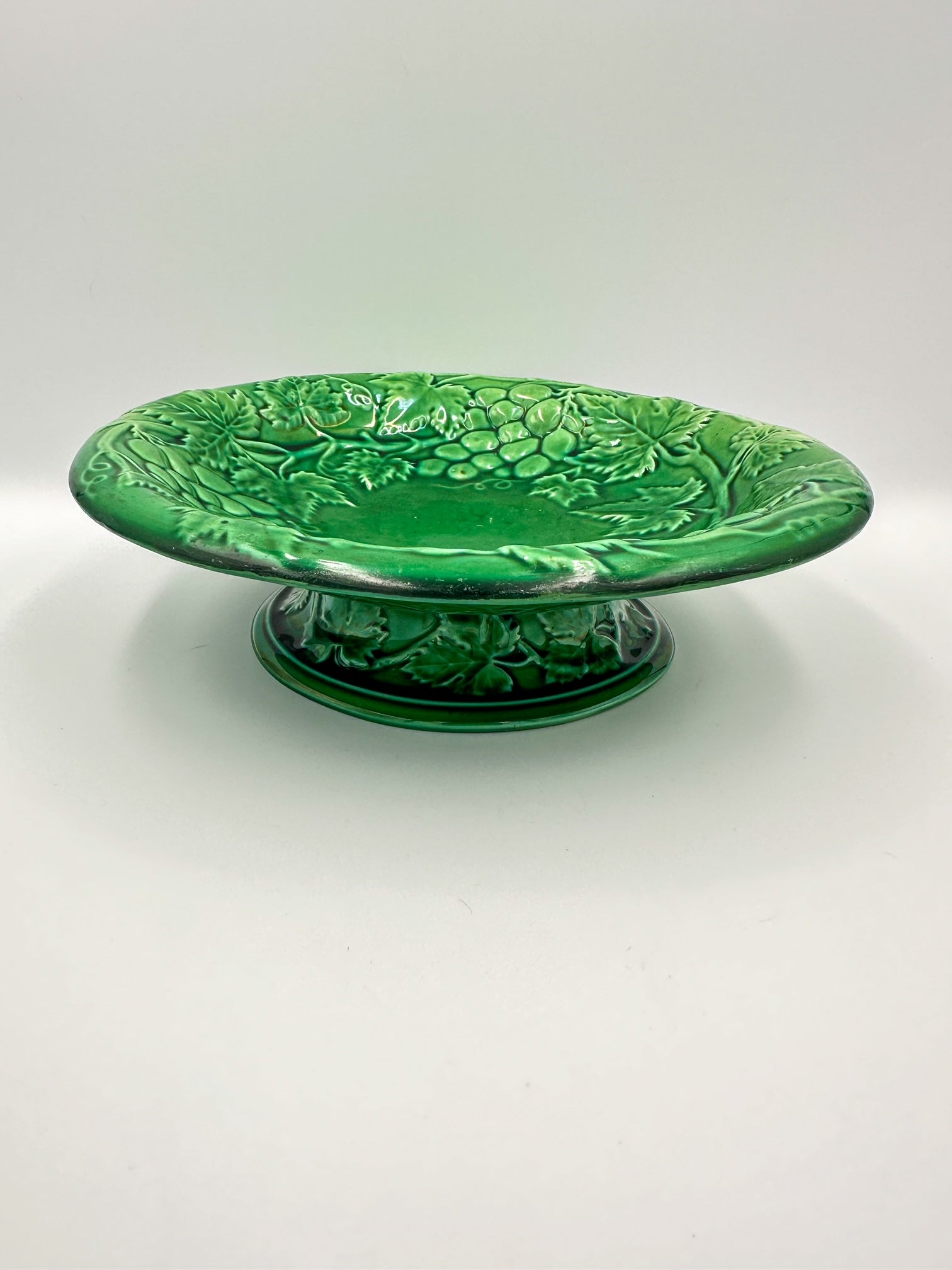 A late 19th century English green majolica footed bowl with a grape vine pattern, unmarked on the bottom.