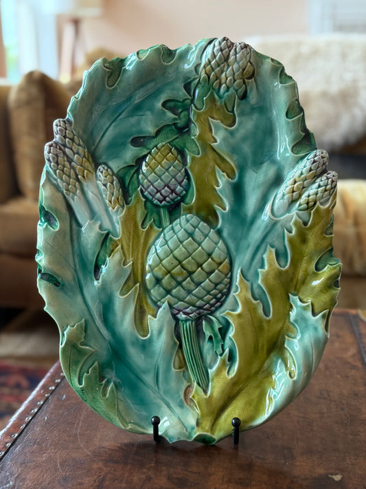 A turquoise, purple, and green serving platter with asparagus and artichokes in the barbotine majolica style. 