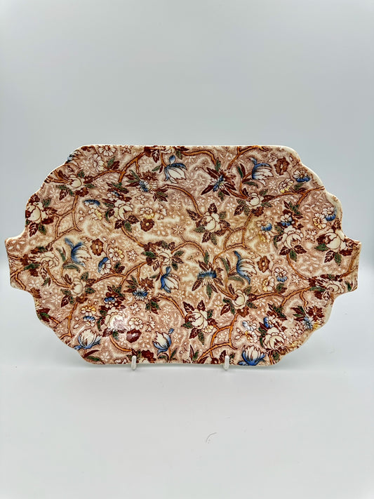 A brown and blue chintz ceramic serving dish with floral patterns on a white background.