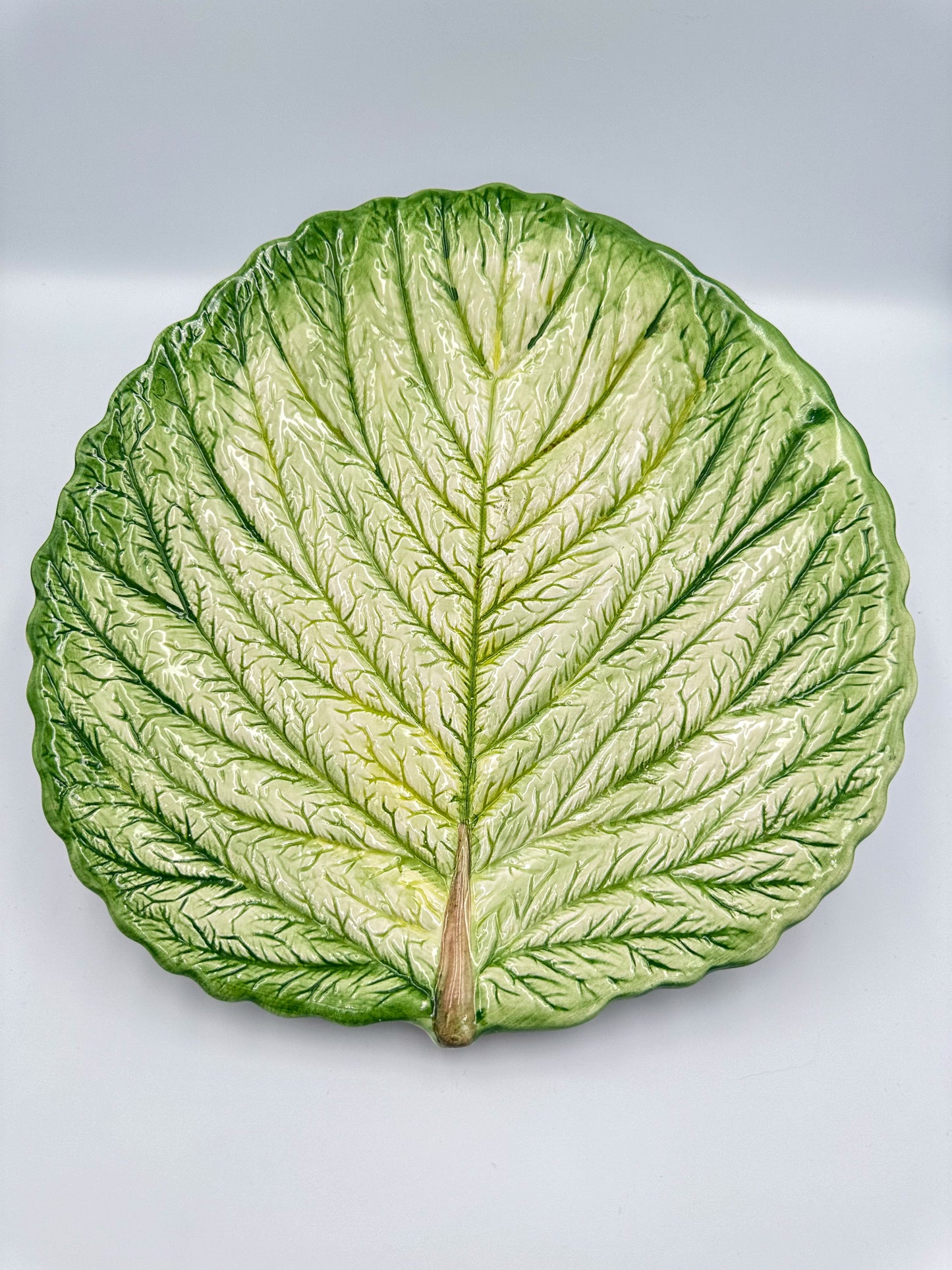 A vintage French cabbage leaf-shaped majolica serving platter with a raised relief stalk and veins, in natural glazed colors.