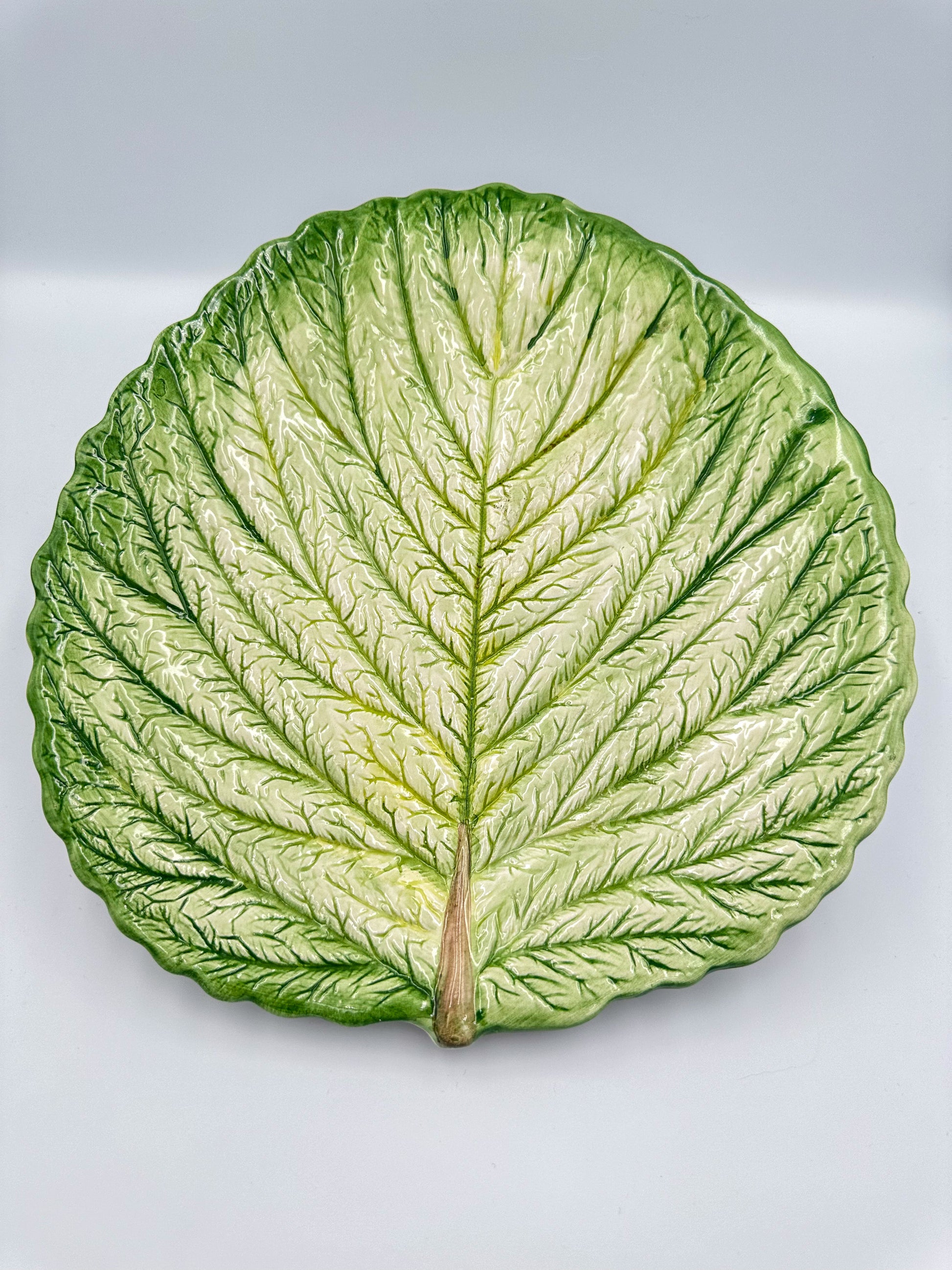 A vintage French cabbage leaf-shaped majolica serving platter with a raised relief stalk and veins, in natural glazed colors.