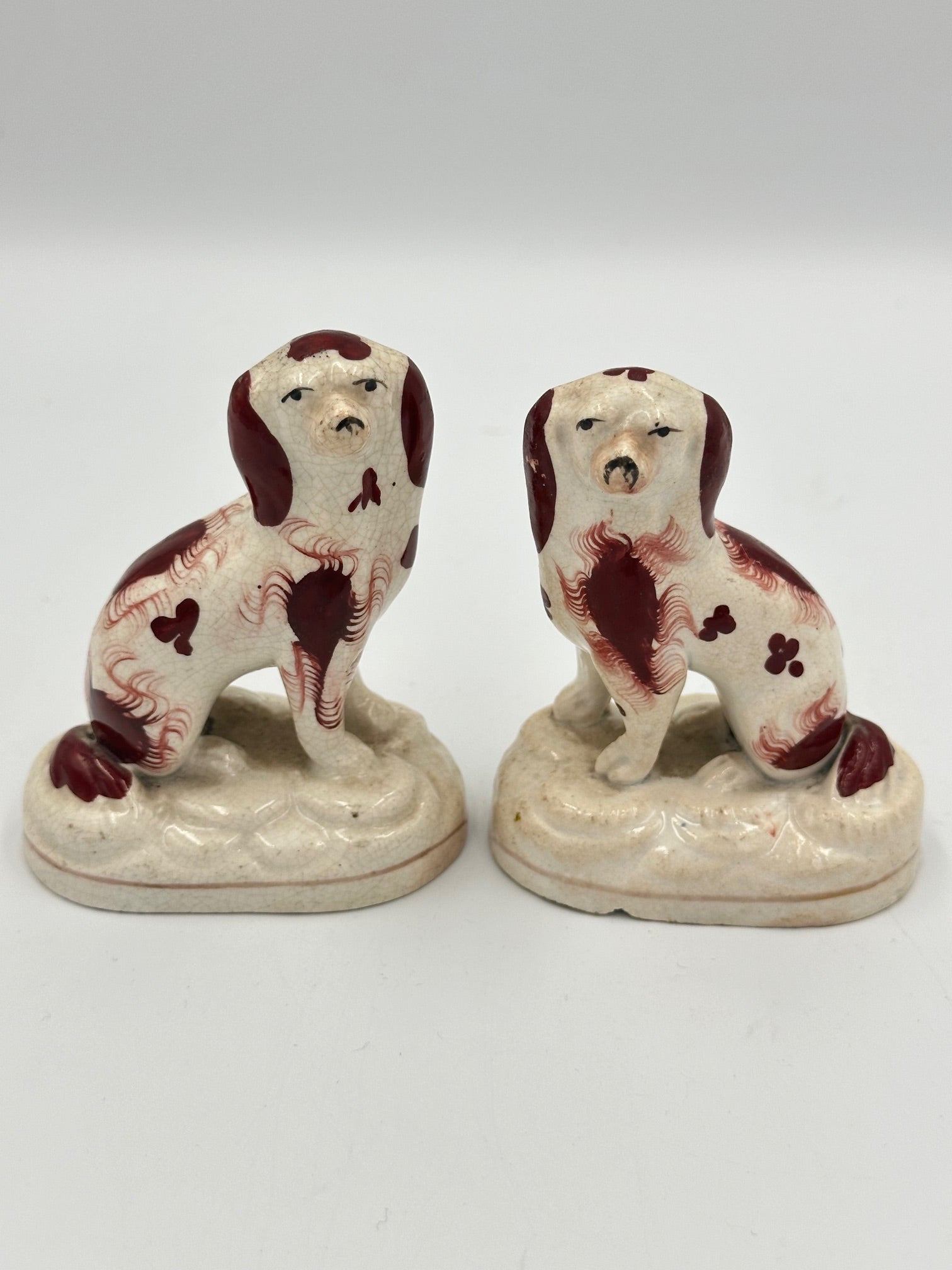 A pair of miniature mounted red Staffordshire Spaniels, showing signs of wear and age.