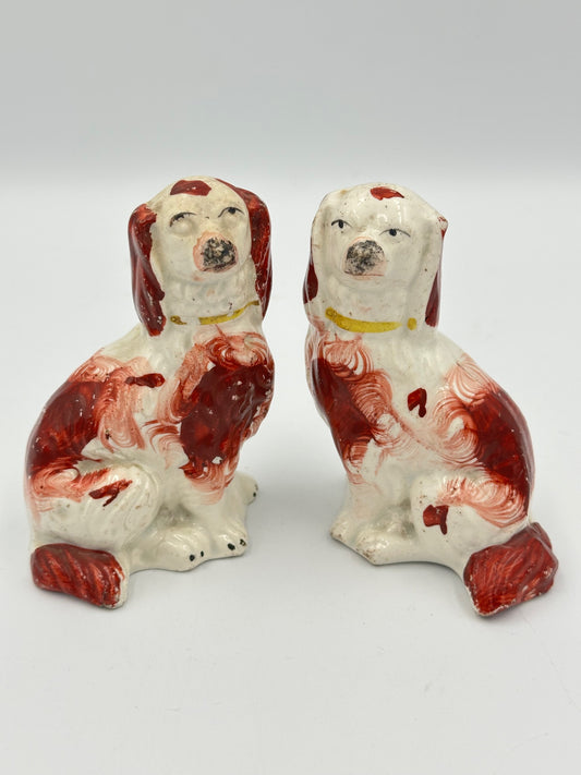 A pair of miniature red Staffordshire Spaniels with white and red paintwork, showing signs of wear and aging.