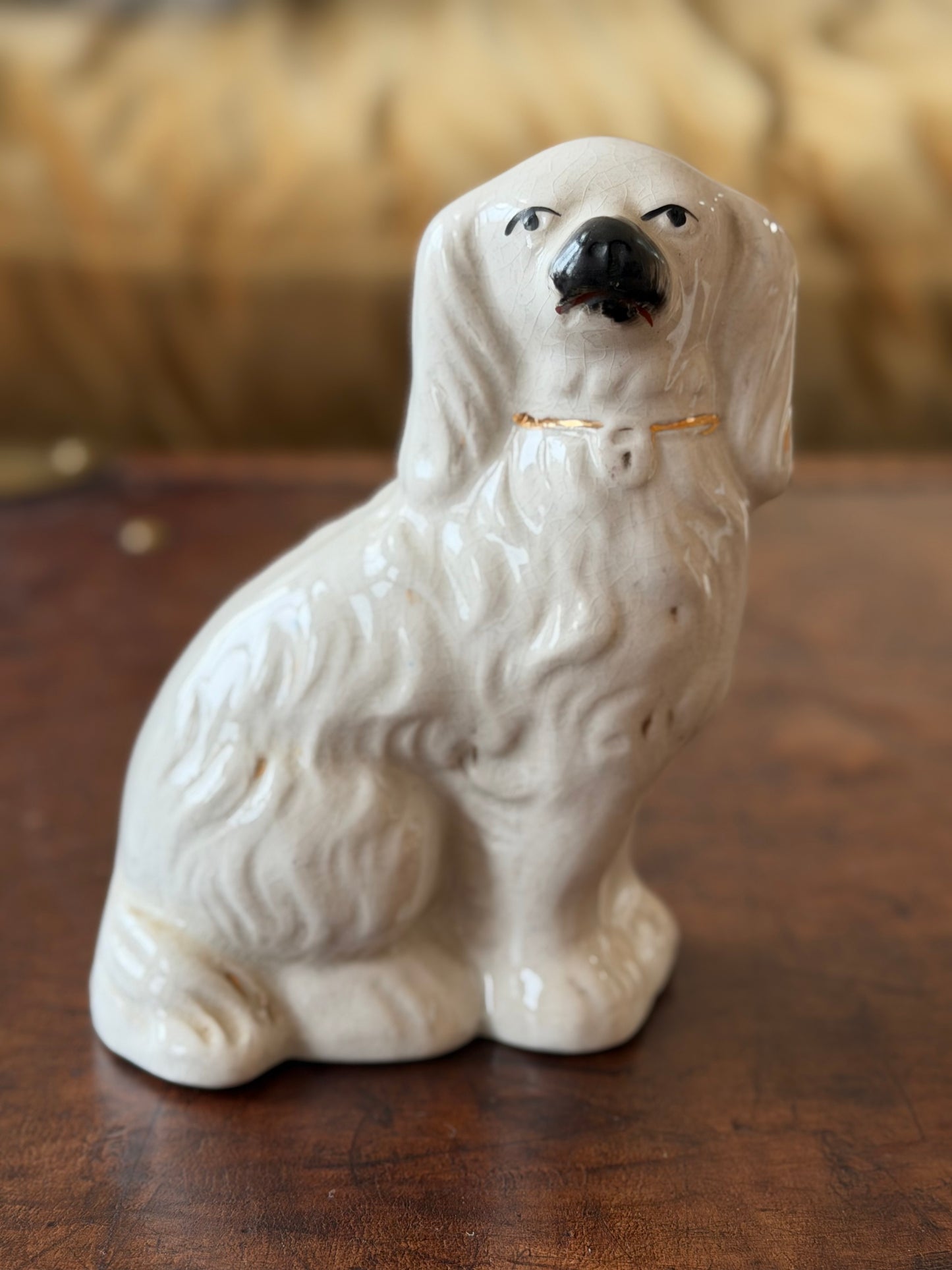 Small white staffordshire dog ceramic figurine with handpainted facial features and gold collar details. 