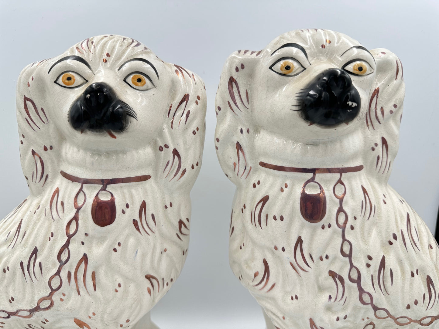 A pair of antique white Staffordshire King Charles Spaniels with pink lustre fan accents.