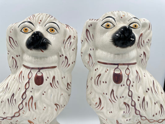 A pair of antique white Staffordshire King Charles Spaniels with pink lustre fan accents.