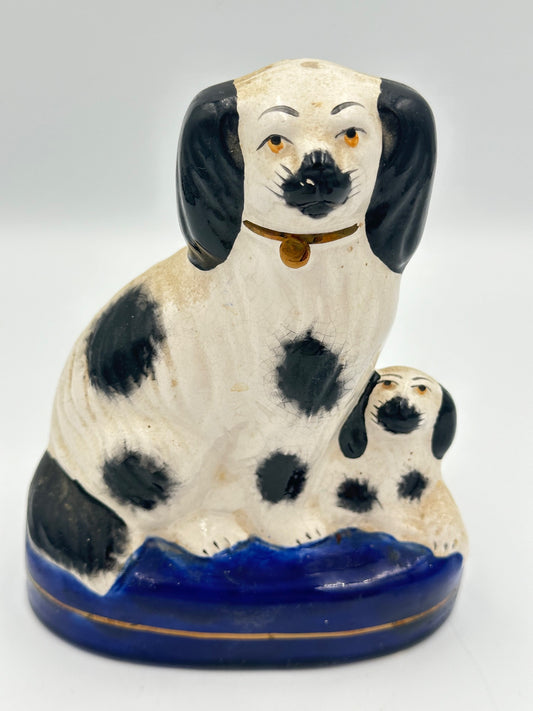 A black and white Staffordshire Spaniel dog and its puppy on a cobalt blue base with a gold stripe, hand painted.