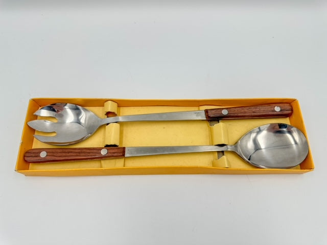 A set of stainless steel salad servers with rosewood handles, displayed in a yellow-colored box.
