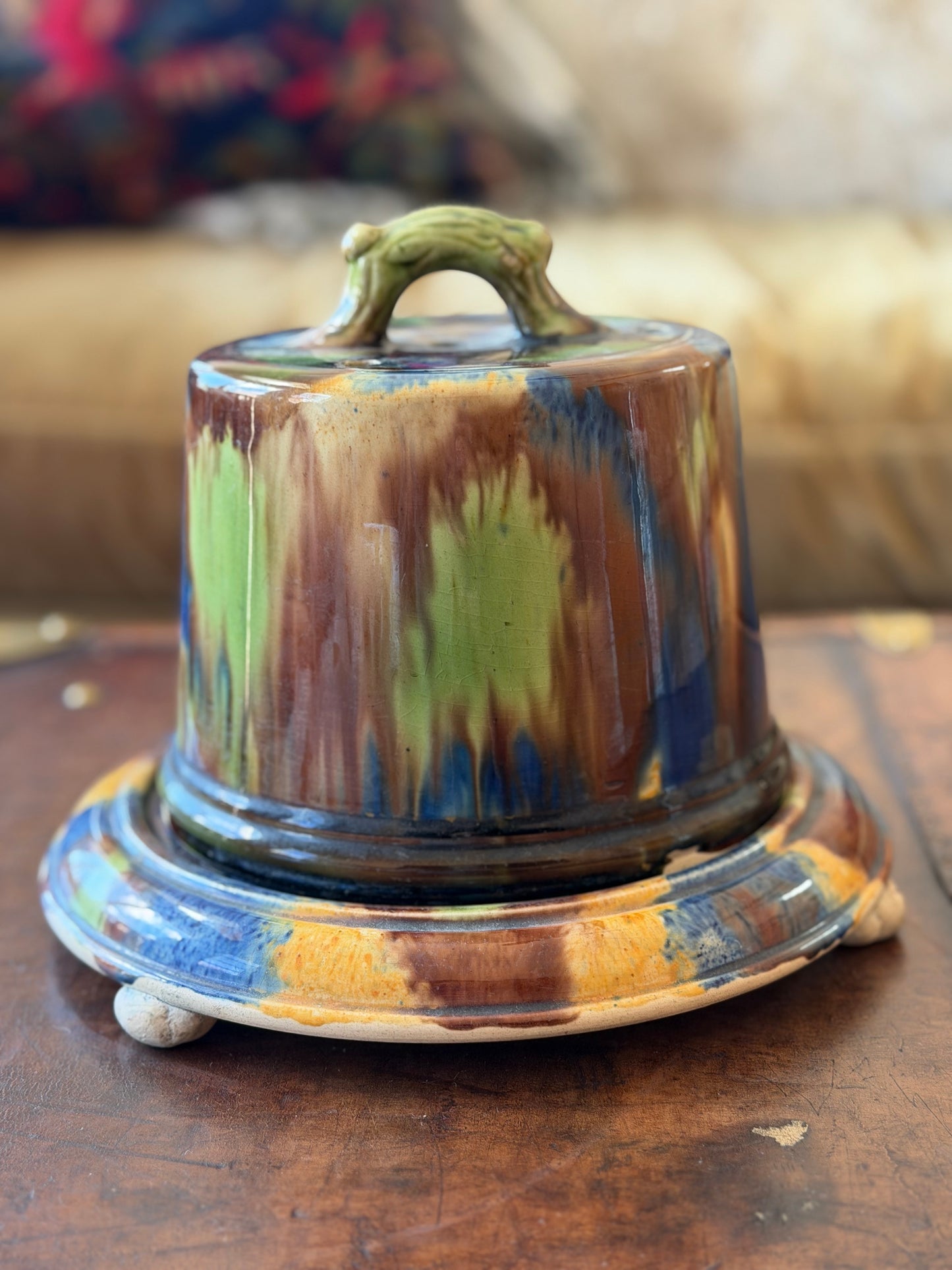 Cheese dish made by Seaton Pottery featuring the green, brown, and blue dab ware style glazing technique. 