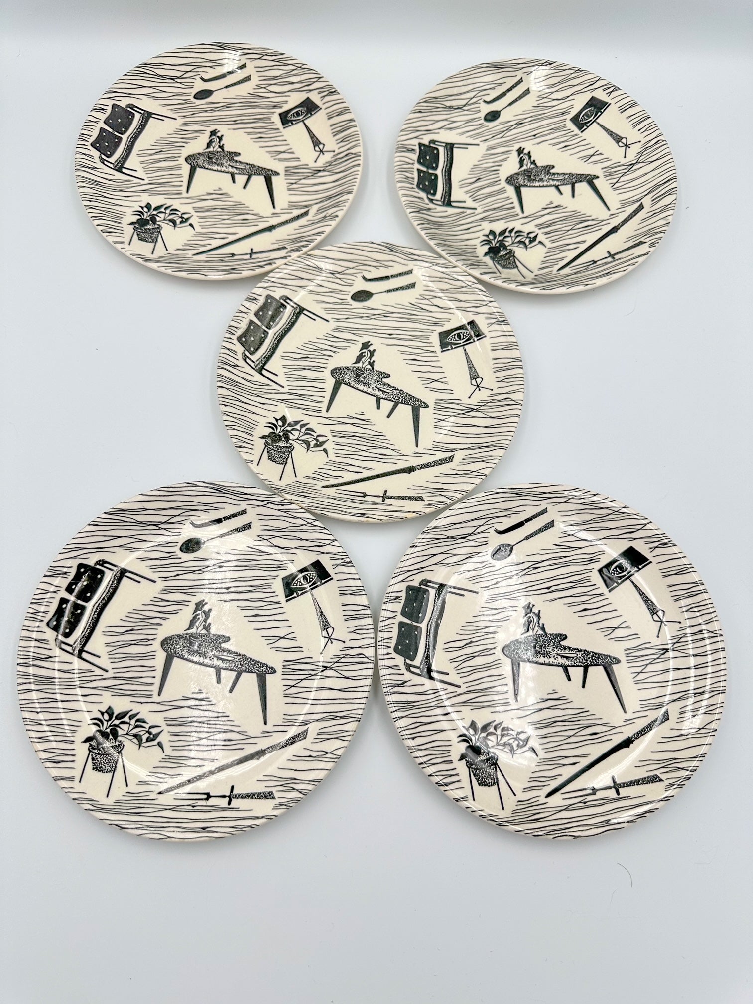 A set of five round ceramic dessert plates with a mid-century homemaker pattern designed by Enid Seeney.