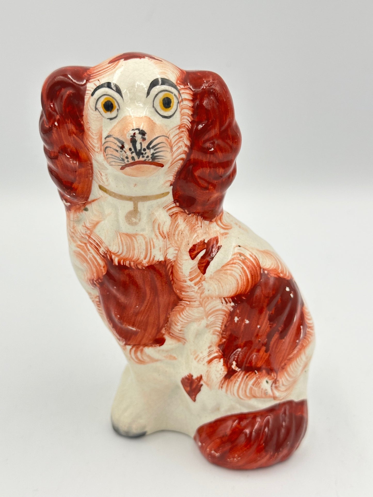 A ceramic figurine of a red Staffordshire King Charles Spaniel with hand-painted details and embossed markings.