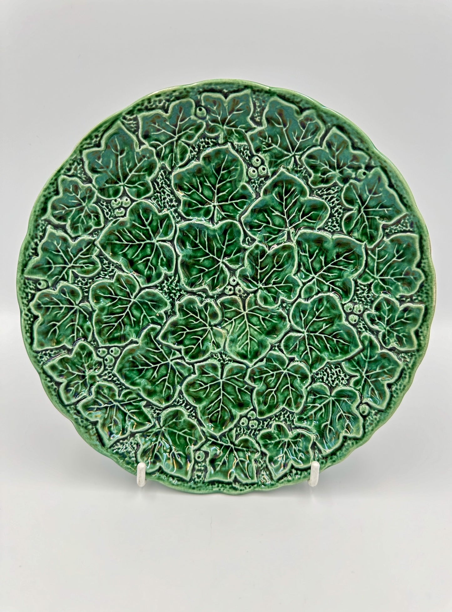 A round green majolica plate with a detailed ivy leaf pattern, made in England in the early 20th century.