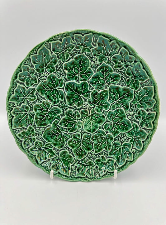 A round green majolica plate with a detailed ivy leaf pattern, made in England in the early 20th century.