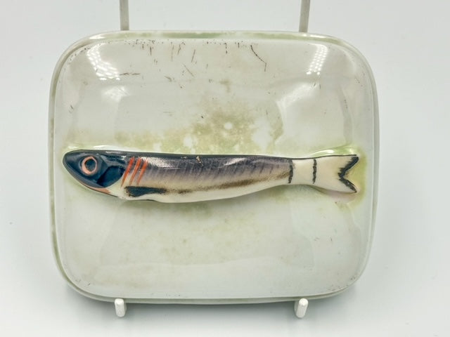 A porcelain lustreware sardine dish with a fish handle on the lid, featuring a simulated fish scale pattern on the sardine.