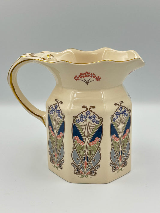 A vintage Liberty Art Nouveau ceramic pitcher with floral patterns and a gold handle, made in England.
