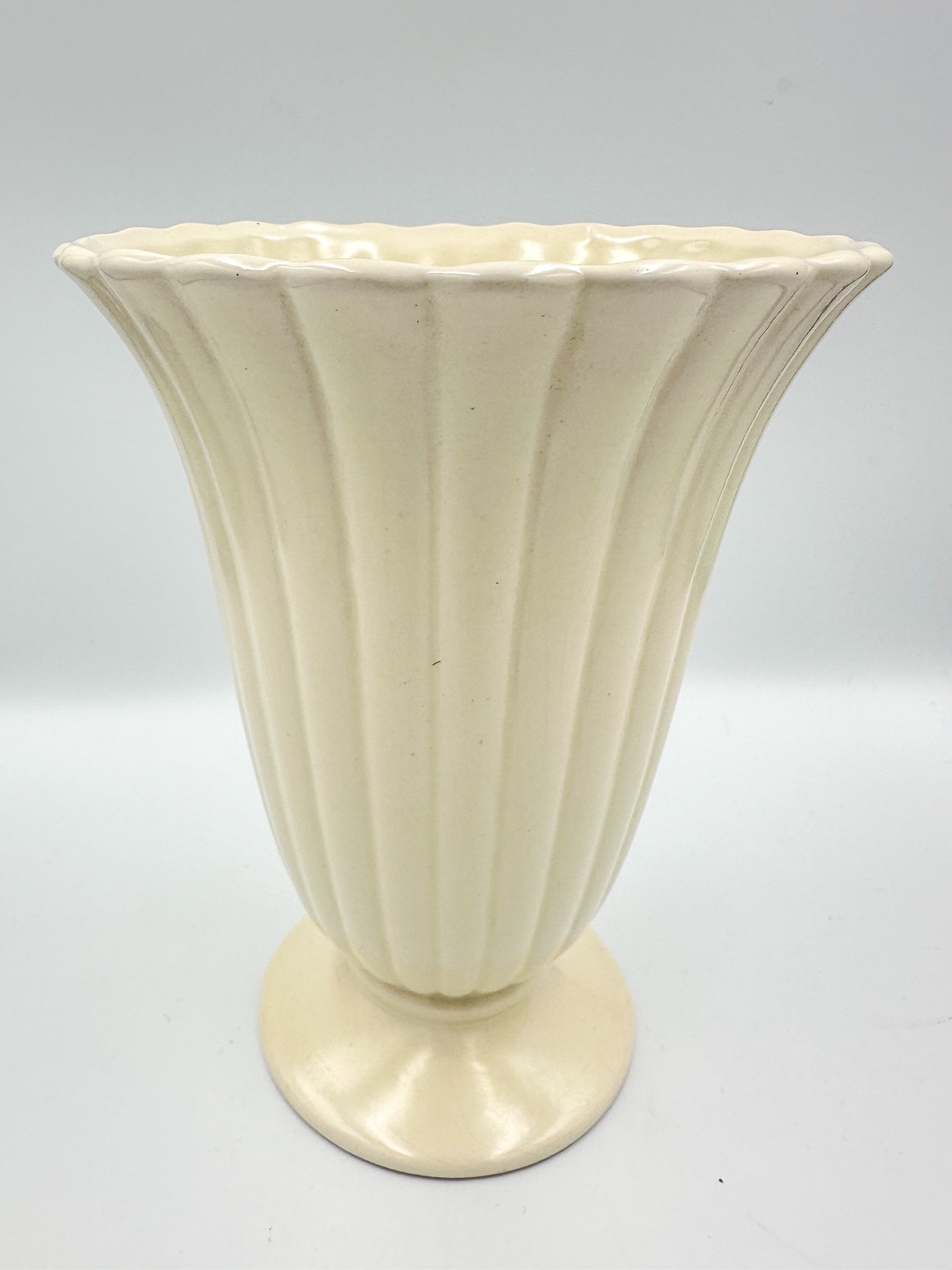 A vintage ribbed creamware vase with a beige color, early 20th century design, and a solid pattern.